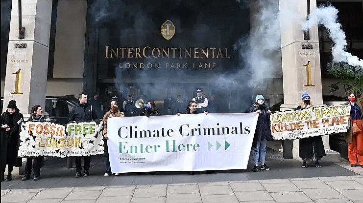 Các nhà hoạt động vì khí hậu đốt pháo sáng và giương biểu ngữ trong cuộc biểu tình bên ngoài khách sạn InterContinental London Park Lane vào ngày đầu tiên của sự kiện Tuần lễ Năng lượng Quốc tế ở London 
