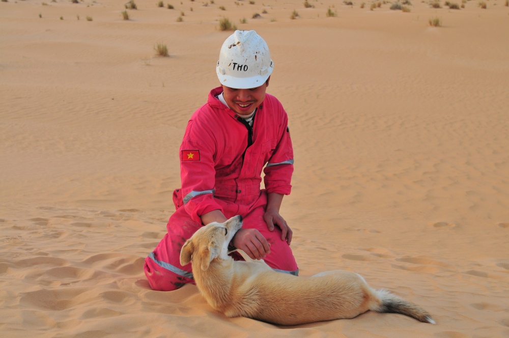 18-DQL-AB-0001-09: Phút thư giãn vui đùa giữa những giờ lao động hăng say, chú chó trong ảnh là 1 người bạn thân thiện lang thang khắp sa mạc và đồng hành với giàn PV Drilling 11 từ khoan trường này đến khoan trường khác.