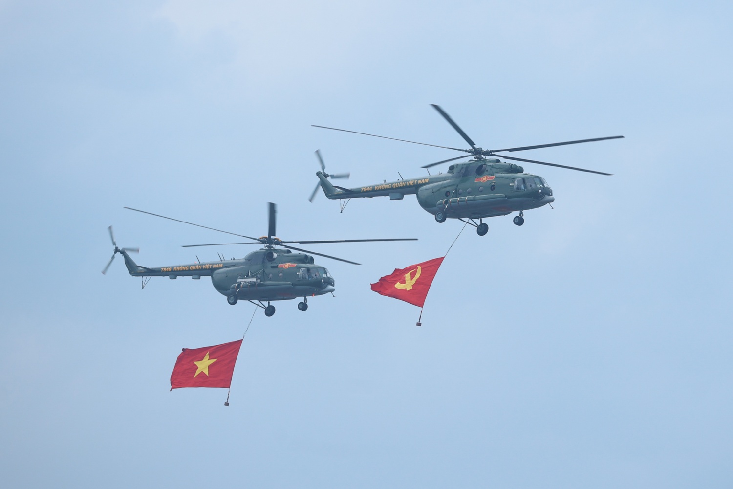 Các biên đội trực thăng vũ trang thuộc Quân chủng Phòng không - Không quân, Quân đội nhân dân Việt Nam mang theo cờ Đảng, cờ Tổ quốc Việt Nam diễu hành tiến qua sân vận động Điện Biên - Ảnh: VGP/Nhật Bắc