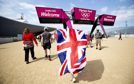 Một du khách với lá cờ Vương quốc Anh trên người tiến vào khu vực Công viên Olympic