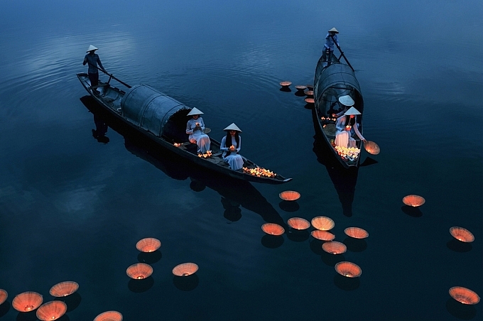 Bức ảnh Cầu siêu của Bùi Phú Khánh ghi lại khoảnh khắc những cô gái Việt mặc áo dài đội nón lá thả hoa đăng trên sông