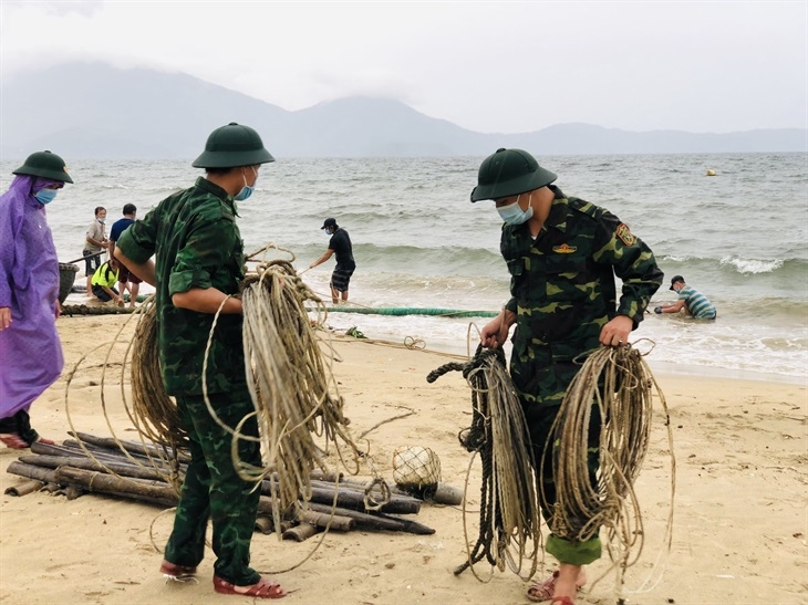 Cán bộ Đồn Biên phòng Phú Lộc giúp ngư dân thu cất ngư lưới cụ. Ảnh: Trúc Hà