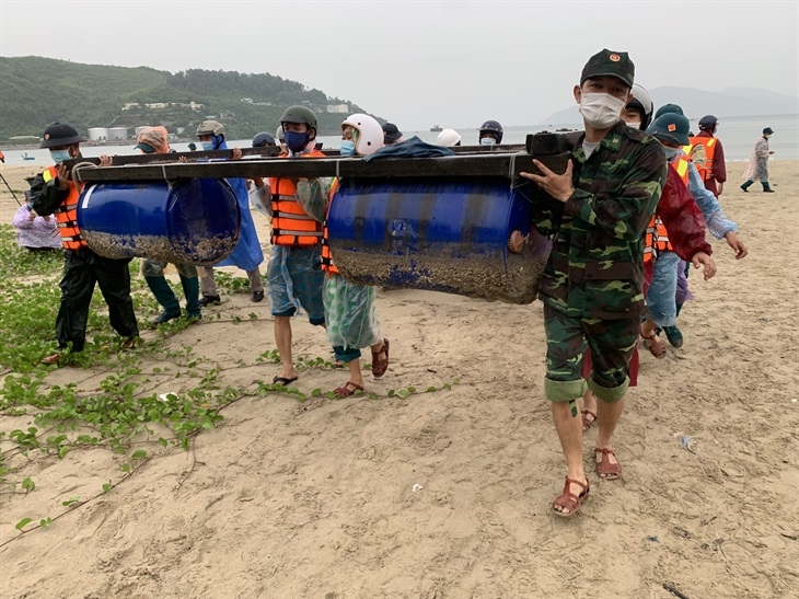 Cán bộ, chiến sĩ Đồn Biên phòng Hải Vân giúp người dân di dời các lồng bè nuôi thủy sản lên bờ. Ảnh: Hồng Quang