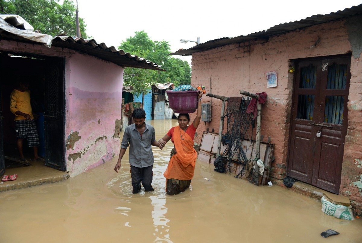 Mưa lớn nhiều ngày qua tại khu vực các bang Gujarat và Rajasthan ở miền tây Ấn Độ đã gây ra tình trạng ngập lụt trên diện rộng, làm hư hại nhà cửa và cơ sở hạ tầng, cản trở giao thông và ảnh hưởng đến đời sống cũng như sinh hoạt của người dân. Trong ảnh: Cảnh ngập lụt sau trận mưa lớn ở Ahmedabad, Ấn Độ ngày 30/7. AFP-TTXVN